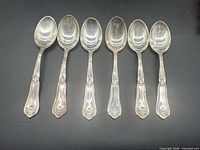 Six .800 silver teaspoons laid out bowl up