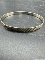 Entire sterling silver textured bangle laid flat