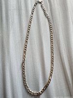 Full view of sterling silver Figaro chain necklace laid flat