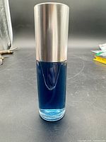 Front view of blue perfume in cylindrical glass bottle with silver cap