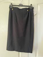 Front of black pencil skirt showing buttons and seams