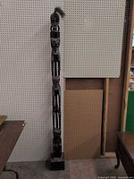 Full view of entire stacked-figure wood sculpture standing on base