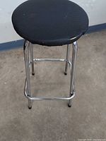 Full view of bar stool showing chrome legs and black seat