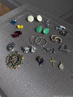 Entire assortment laid out showing all earrings, pendants, brooches and charms