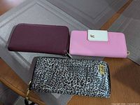 Front view of three wallets—burgundy, pink, leopard print