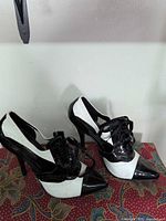 Lateral view of both shoes showing two-tone patent finish and lace-up design