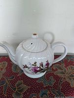 Full view of porcelain teapot music box showing floral design and gold trim