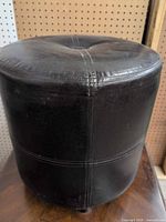 Side view of round bonded leather ottoman