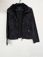 Front view of black Tattoo jacket on hanger showing overall design and pockets