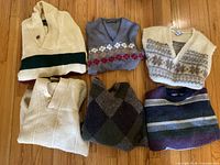 Group shot of all six sweaters and vests folded on floor