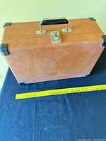 Closed suitcase-style Crosley turntable showing brown faux leather case, handle and latch