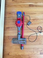 Vacuum main unit attached to brush head, extension wand, and charger laid on floor