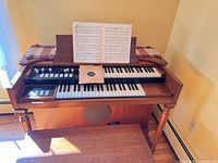 Front view of oak console organ with bench and sheet music displayed