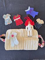 Overall lot showing doll, case and clothing pieces
