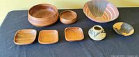 All eight pieces laid out: large and small wooden bowls, terracotta bowl, three square trays, pottery vase, small round dish