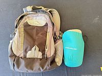 Front view of High Sierra backpack beside teal OstrichPillow travel pillow
