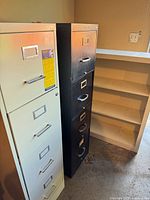 White and black filing cabinets beside off-white bookcase