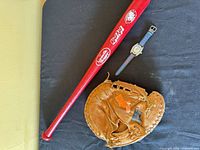 Overview of bat, mitt and watch on black surface