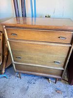 Front view of dresser showing three drawers, tapered legs, metal pulls