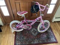Full view of Schwinn pink kids bike with helmet on handlebar