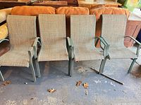 Full front view of four green aluminum patio chairs with tan slings