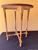 Full view of round wooden end table showing turned legs and stretcher