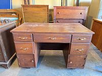 Front view of brown wooden desk showing drawer and cabinet layout