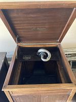 Console phonograph lid open showing tonearm and logo