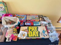 Overview showing Pay Day board game, boxed puzzles, craft bag, marbles/beads