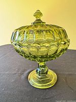 Side view of covered green uranium glass compote on pedestal base