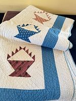 Folded handmade quilt showing basket blocks and blue borders