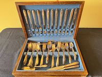 Open wooden chest showing full 48-piece set seated in blue felt slots
