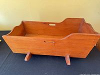 Side view of wooden rocking doll cradle