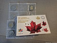 Front view of plastic holder with six coins and Canada 150 folder