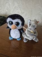 Front view of Waddles penguin and Cheddar mouse plush with tags visible