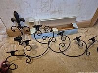 full view of wrought iron sconce with scroll design and glass cups attached
