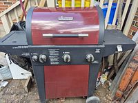 Front view of Brinkmann red and black 3-burner gas grill with cabinet base