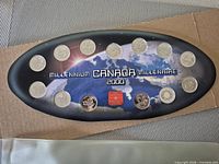 Front view of oval display showing 13 coins mounted around space-themed background