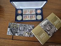 Open case with stamps, coins, booklet, and outer sleeve visible