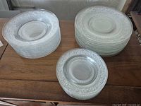 Stacks of clear pressed glass plates: left smaller size, right larger size, front alternate view