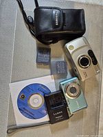 Both cameras, charger, batteries, pouch and CD displayed