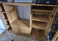 Front view entertainment center showing open TV space, lower cabinet, right glass door section, left shelving