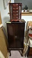 Tabletop jewelry box sitting on floor-standing armoire