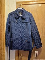 Front view of navy quilted jacket hanging