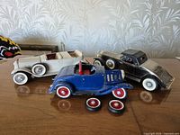 All three die-cast cars and loose wheels on tabletop