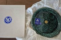 Box with 50th anniversary logo beside platter in packing tissue