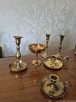 Five brass candle holders and compote on table