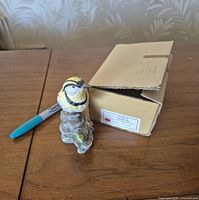 Porcelain meadowlark figurine beside box and marker