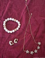 Necklace, bracelet, earrings on fabric background