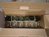 Open box showing twelve separated tumblers, six green textured, six clear smooth